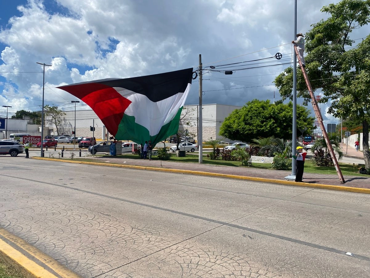 Decenas de personas despliegan una bandera a favor de Palestina en Cancún